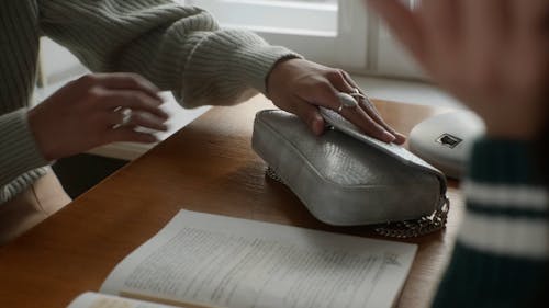 A Person Taking out Pressed Powder from a Handbag