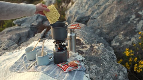 A Person Cooking Instant Noodles on a Camping Stove