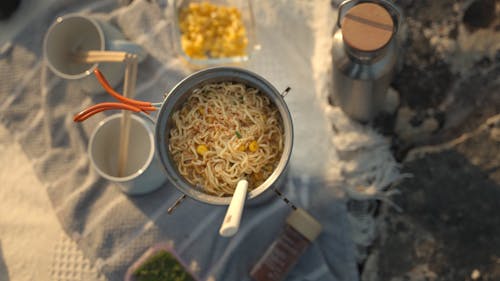 A Person Cooking Noodles while on a Camping 