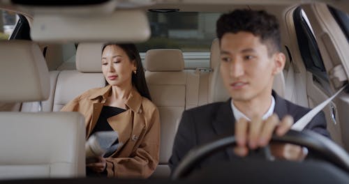 A Businesswoman Reading a Newspaper Inside a Moving Car