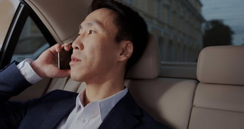 A Man in the Backseat of a Car Talking on the Phone 