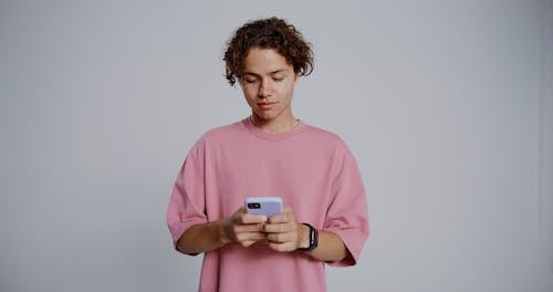 Man Wearing Pink Shirt Using a Cellphone