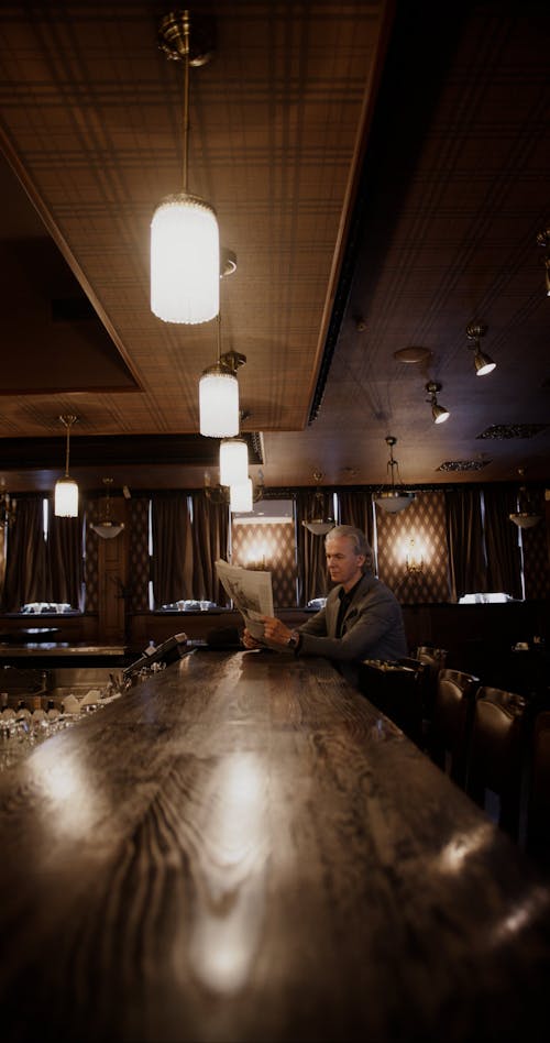 Person Reading a Newspaper at the Bar Counter