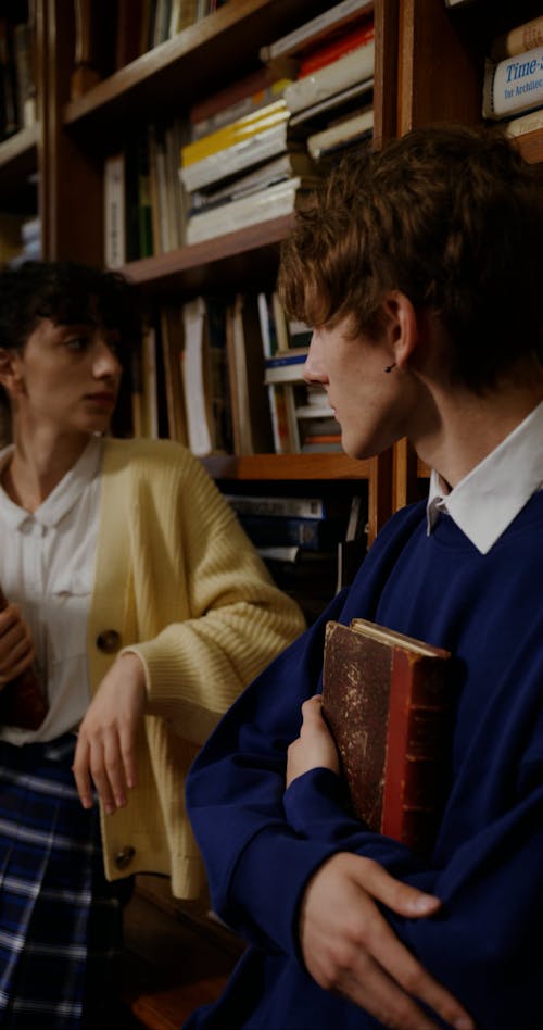 A Man and Woman Talking Inside the Library while Holding Books