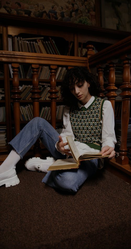 Woman Flipping Pages of a Book while Sitting on the Floor