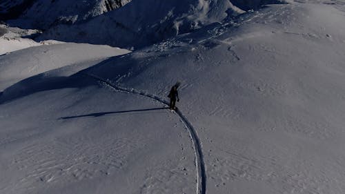 Drone shot of man hiking in mountains in winter