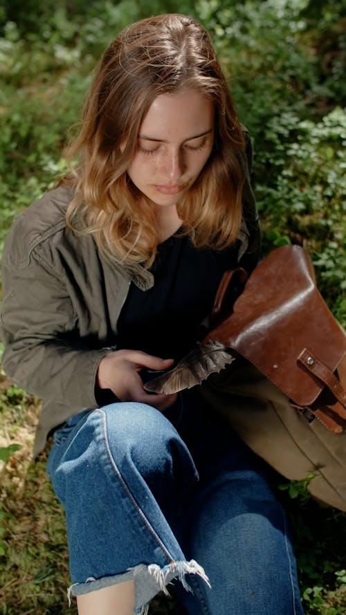 A Woman Touching a Feather on Her Backpack