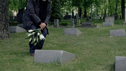 Man Putting Flowers on a Grave