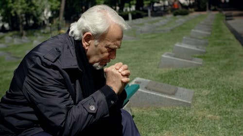 Sad Man Sitting on Bench at the Cemetery