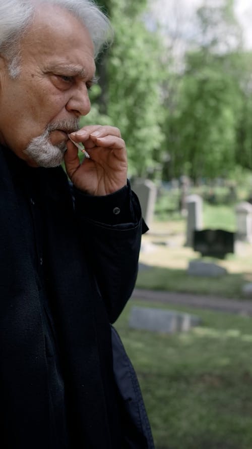 Elderly Man Smoking Cigarette at the Cemetery