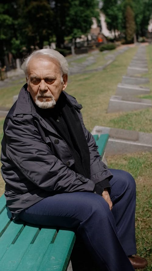 Elderly Man Sitting on Bench at the Cemetery