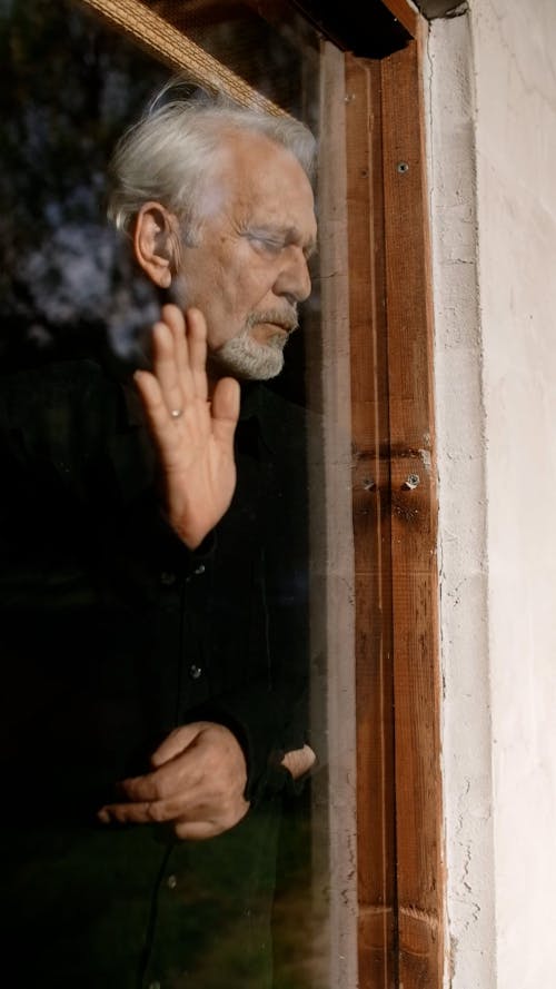 Elderly Man Leaning on a Glass Window