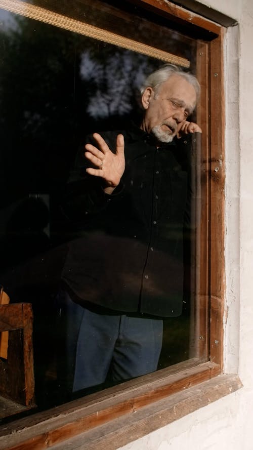 Sad Man Touching a Glass Window