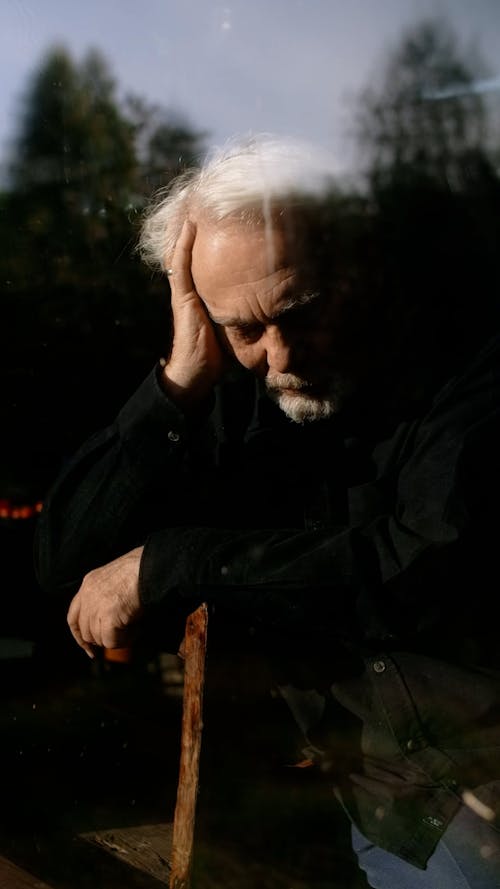 A Grieving Elderly Man behind a Window Glass