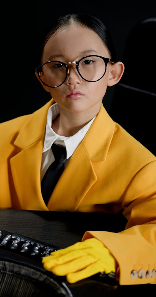 A Child in a Yellow Suit Typing on a Typewriter
