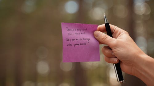 A Person Holding a Note and a Pen