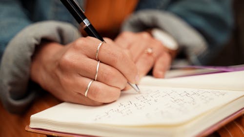 A Person Writing on a Notebook