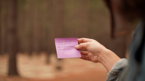 Close up of a Person Sticking a Note in a Notebook