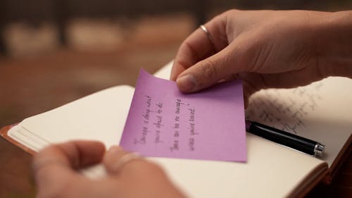 Close up of a Person Sticking a Note in a Notebook