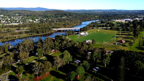 Drone shot of river with bridge and soccer pitch