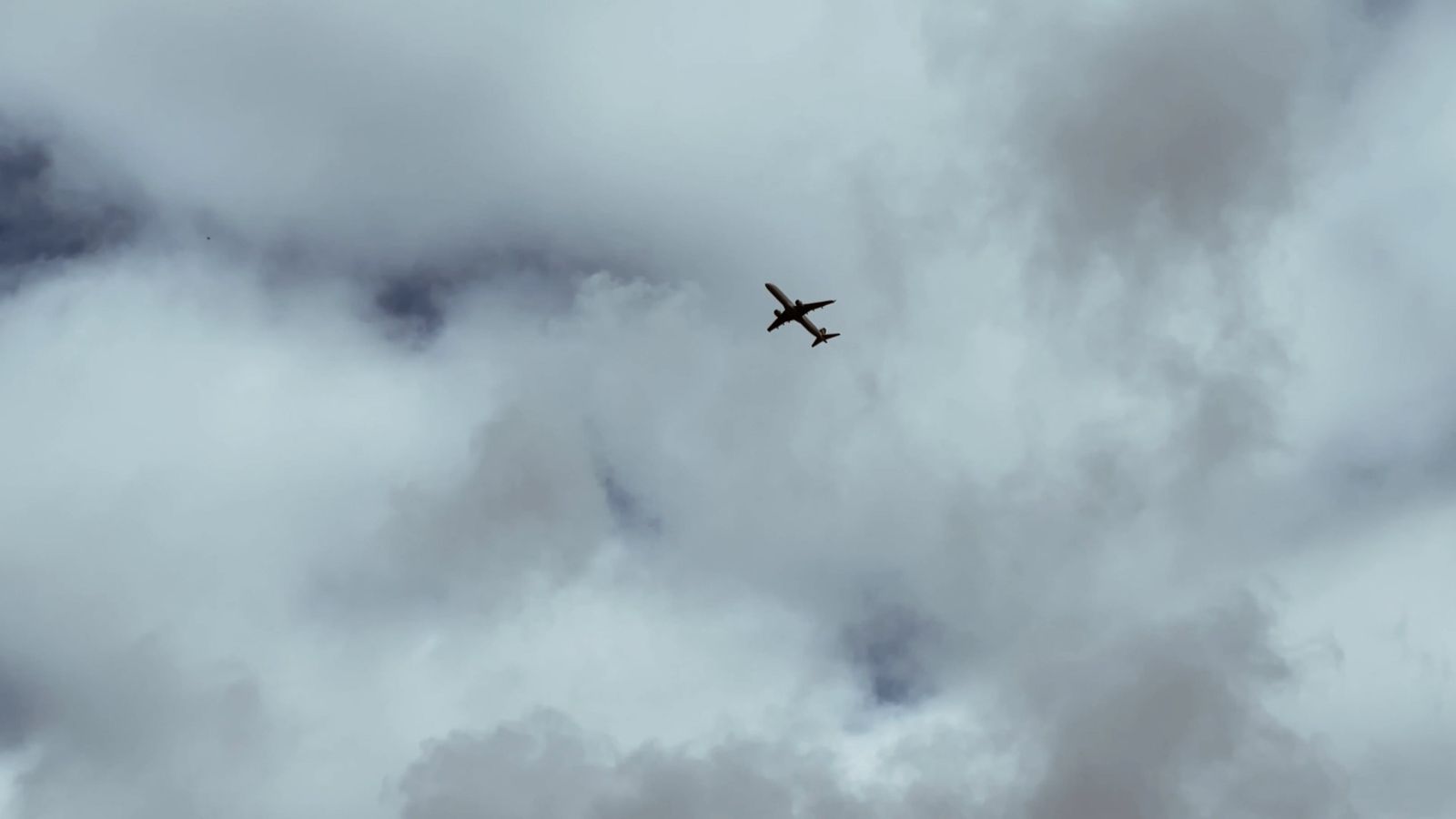 A plane flying through the cloudy sky with a blue sky Free Stock Video ...