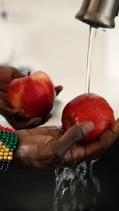 Close-up of woman cleaning fruit in sink