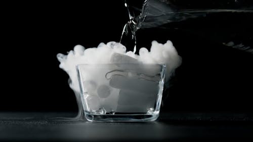 Person pouring water on dry ice in bowl