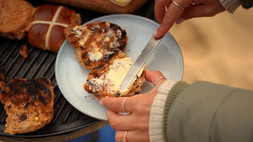 A Person Spreading Butter on a Bread 