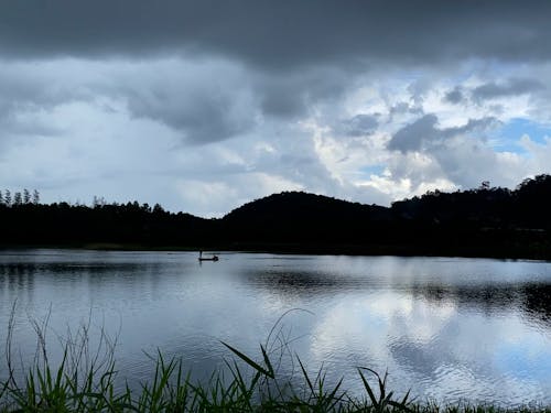 Dark clouds over lake surrounded by hills