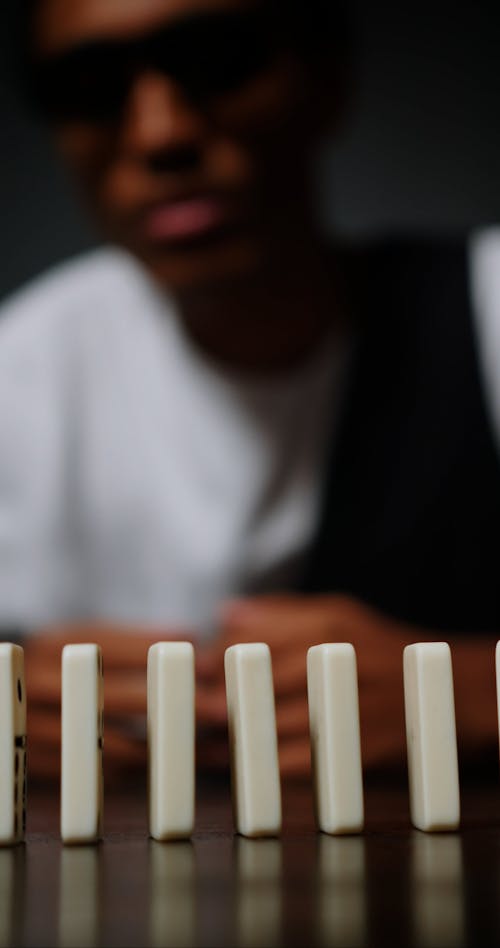 A Man Picking Up a Domino