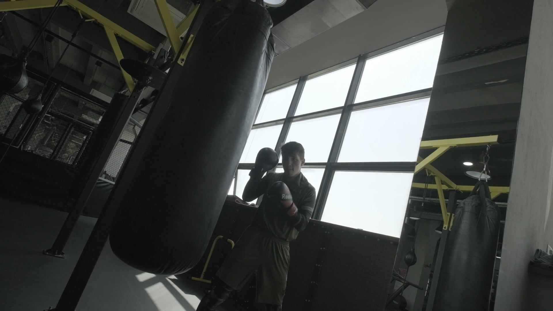 A boxer working the heavy bag in a dim gym