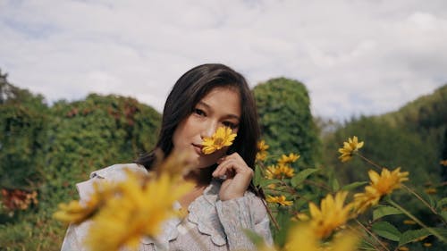 A Beautiful Woman Smelling a Yellow Flower