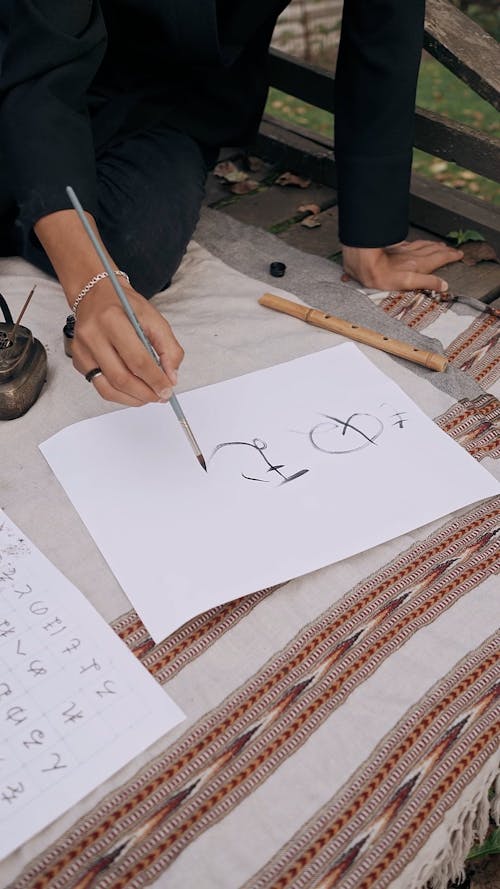 A Person Writing Japanese Letters on Paper 