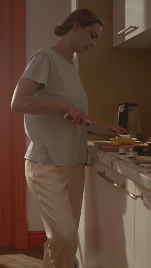 A Woman Slicing a Food on the Kitchen