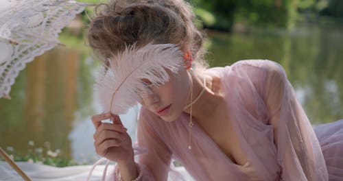 Woman in Marie-Antoinette stylization playing with feather