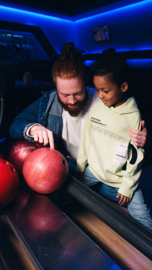 Man and girl holding bowling ball