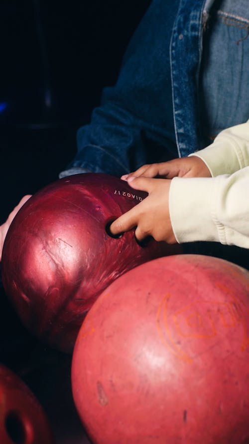 Close up view of girl trying to pick up bowling ball
