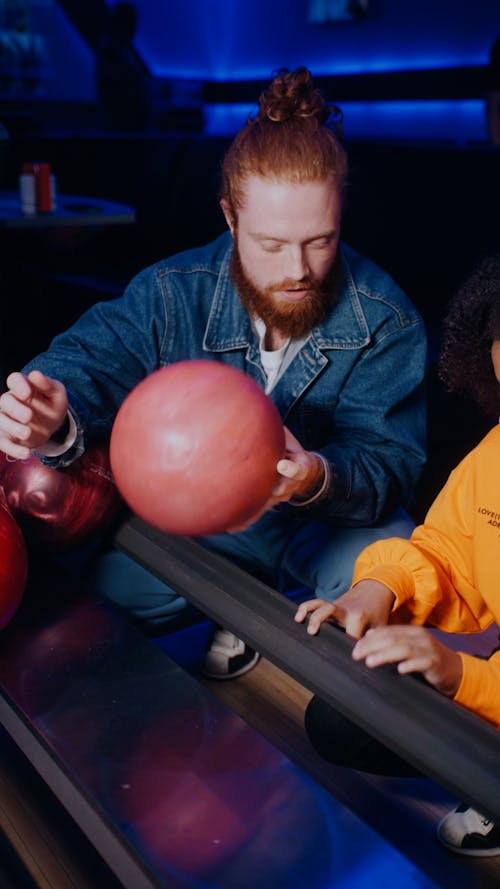 A Man Teaching a Girl How to Hold a Bowling Ball