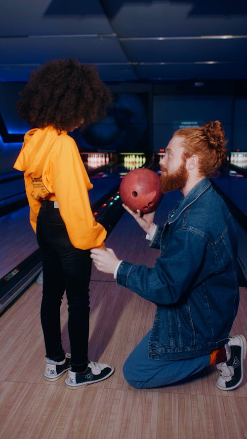A Man Teaching a Child How to Put On a Bowling Ball