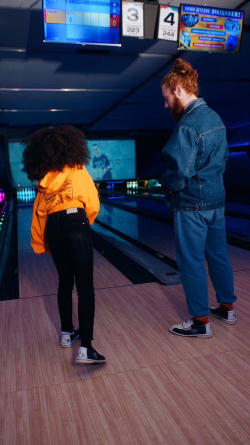 Rear view of man and girl bowling