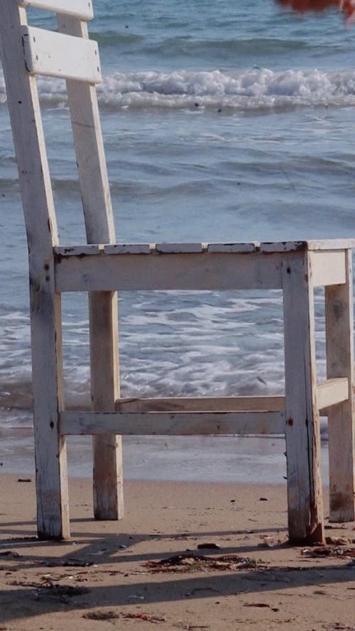 Person Putting Flowers on Chair on Beach