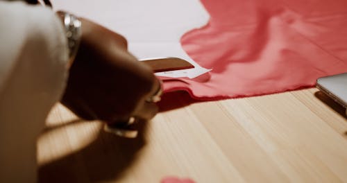 A Fashion Designer Cutting a Red Fabric