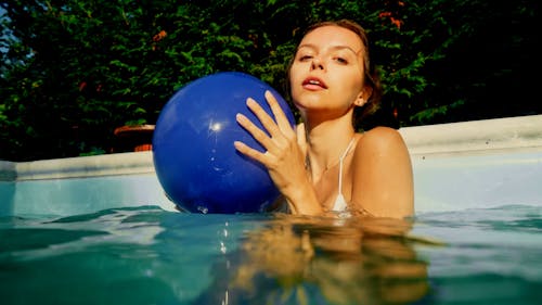 A Woman in a Swimming Pool Bouncing a Ball on the Camera