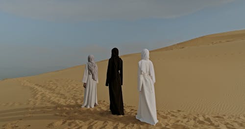 Three Women Walking over Footprints on Desert