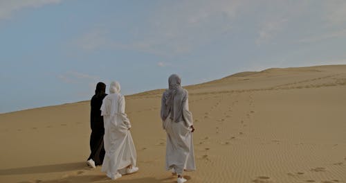 Rear View on Three Women Walking on Desert
