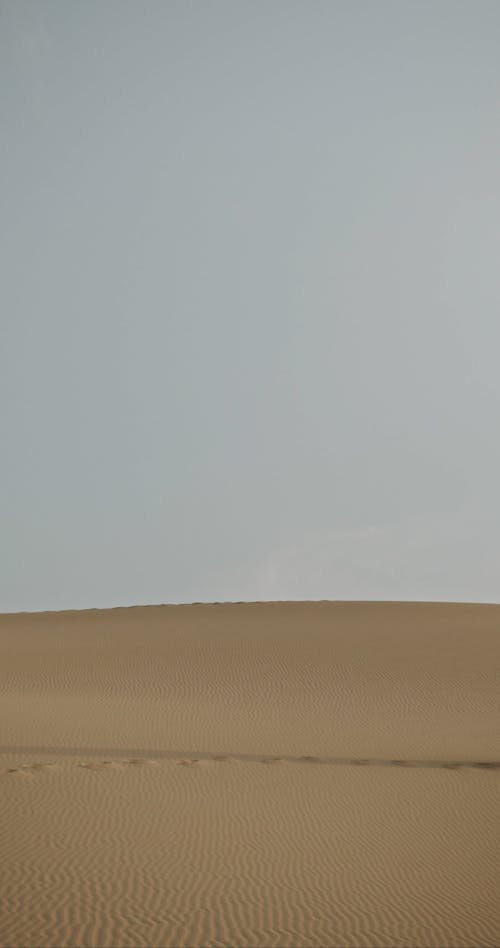 A Person Walking in the Middle of the Desert while Wearing Hijab