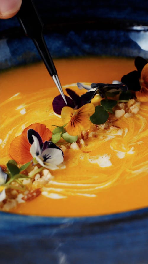 A Person Putting Garnish on a Pumpkin Soup