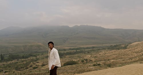 Man in White Shirt Standing on Desert near Valley