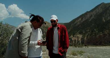 a man holding a drone controller while looking up with his friends