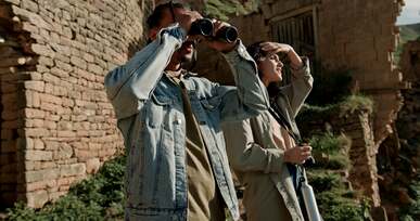 tourists with binoculars near old ruins